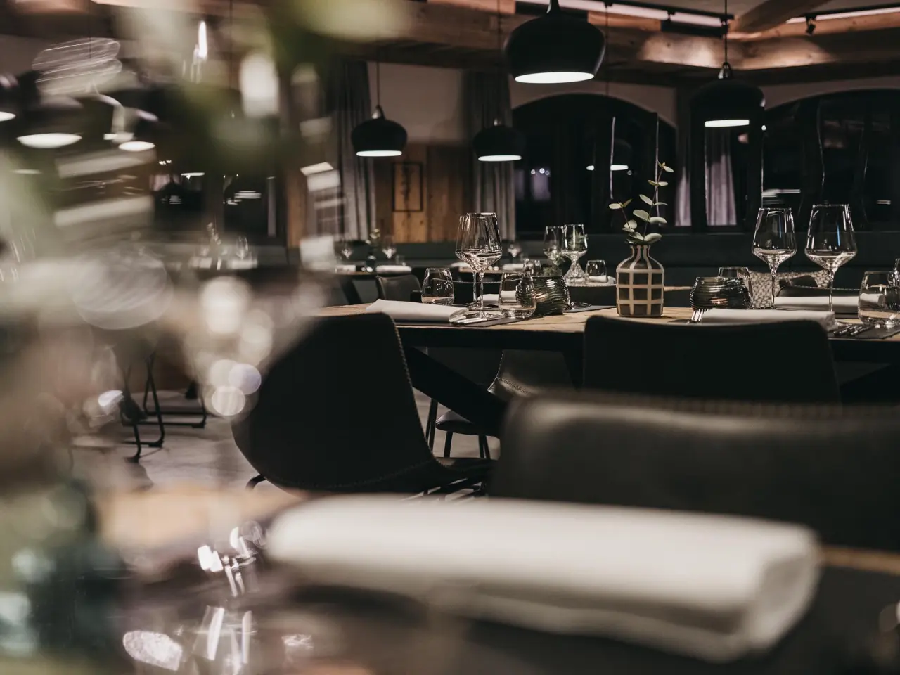 Elegant gedeckter Tisch im Restaurant des VAYA Zillertal mit stilvoller Beleuchtung und moderner Einrichtung.