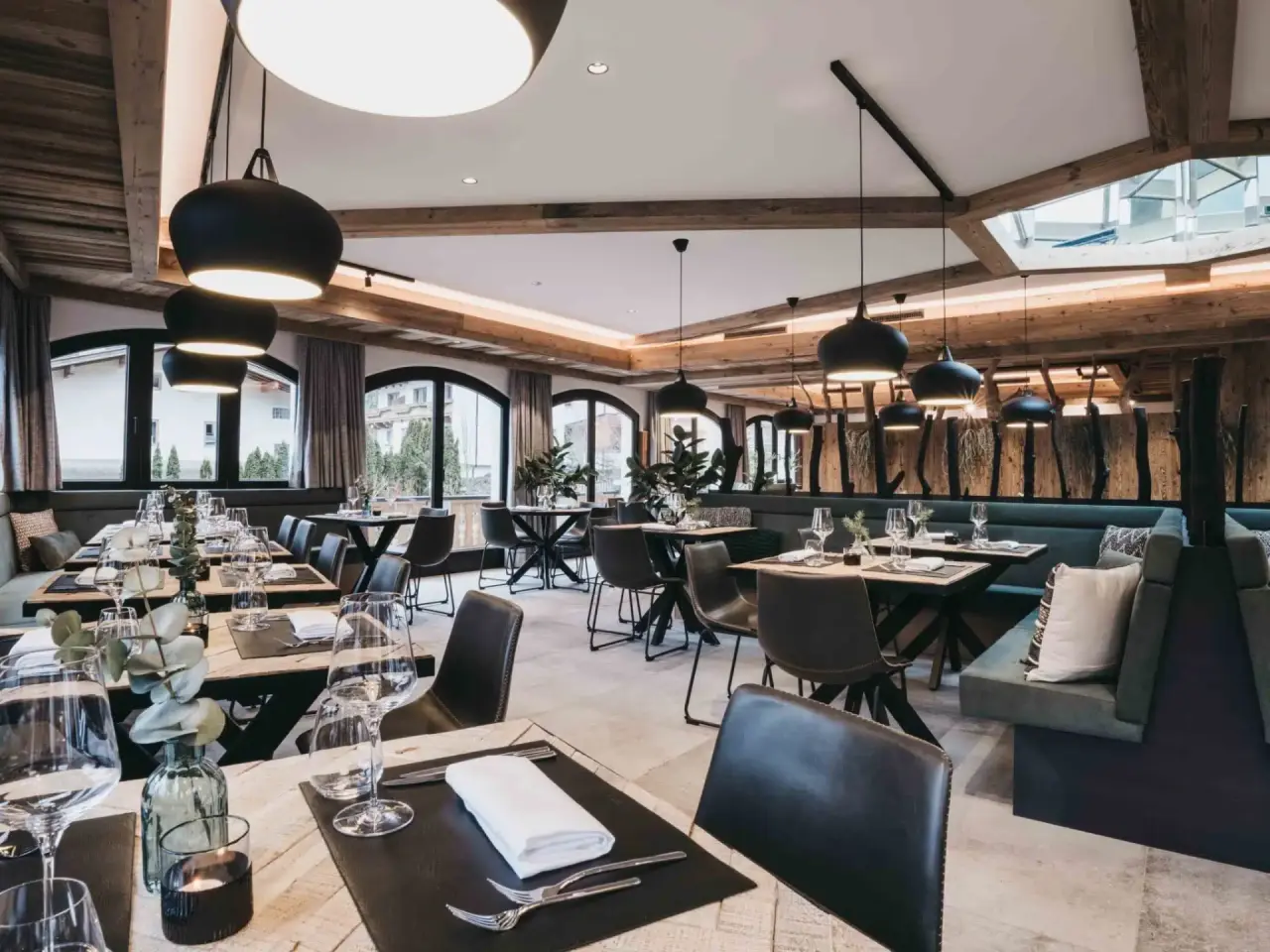 Modernes Restaurant im alpinen Stil mit Holzbalken und elegant gedeckten Tischen im VAYA Zillertal.