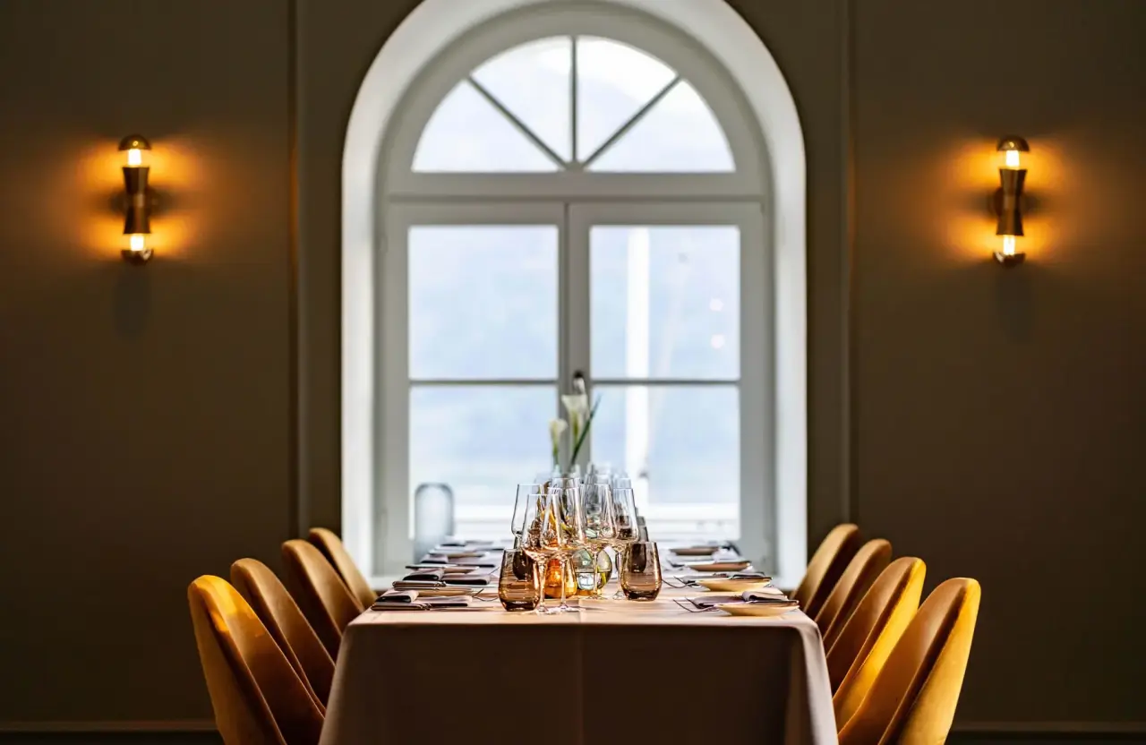 Elegantes Restaurant mit festlich gedecktem Tisch und Bogenfenster im Hotel DAS TEGERNSEE.