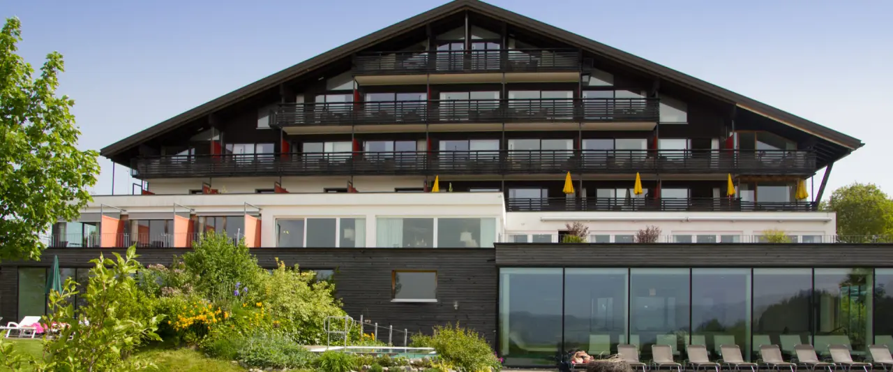 Aussenansicht des Wellnesshotel Linde mit Balkonen, Garten und Blick auf den Indoor-Poolbereich.