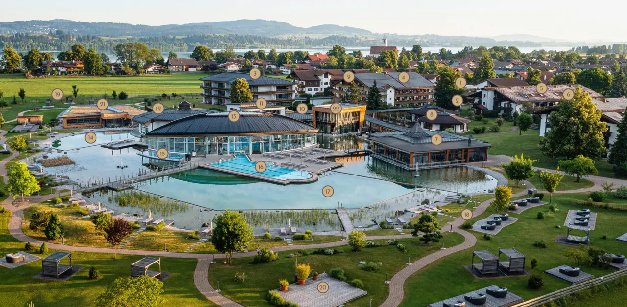 Luftaufnahme des König Ludwig Inspiration SPA mit weitläufiger Pool- und Seenlandschaft, umgeben von Hotelgebäuden und Natur.