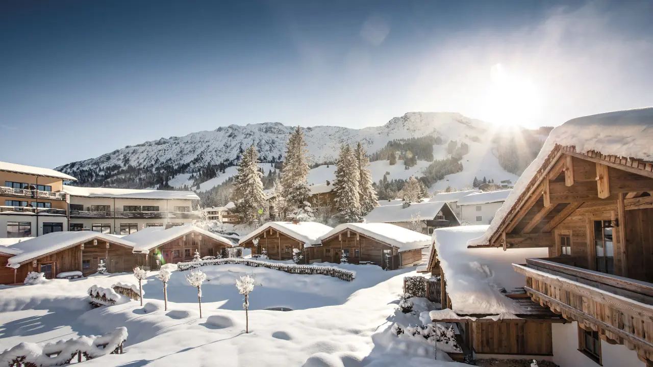 Verschneite Alpin Chalets Oberjoch mit majestätischem Bergpanorama im Winter unter strahlender Sonne.
