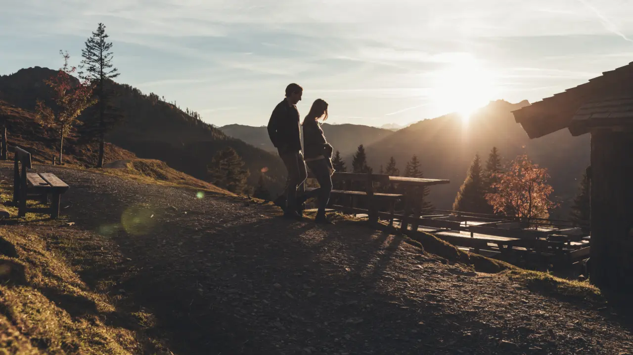 Romantischer Sonnenuntergang mit wanderndem Paar und Alpenpanorama nahe dem Hotel Nesslerhof. Perfekt für Naturerlebnisse.