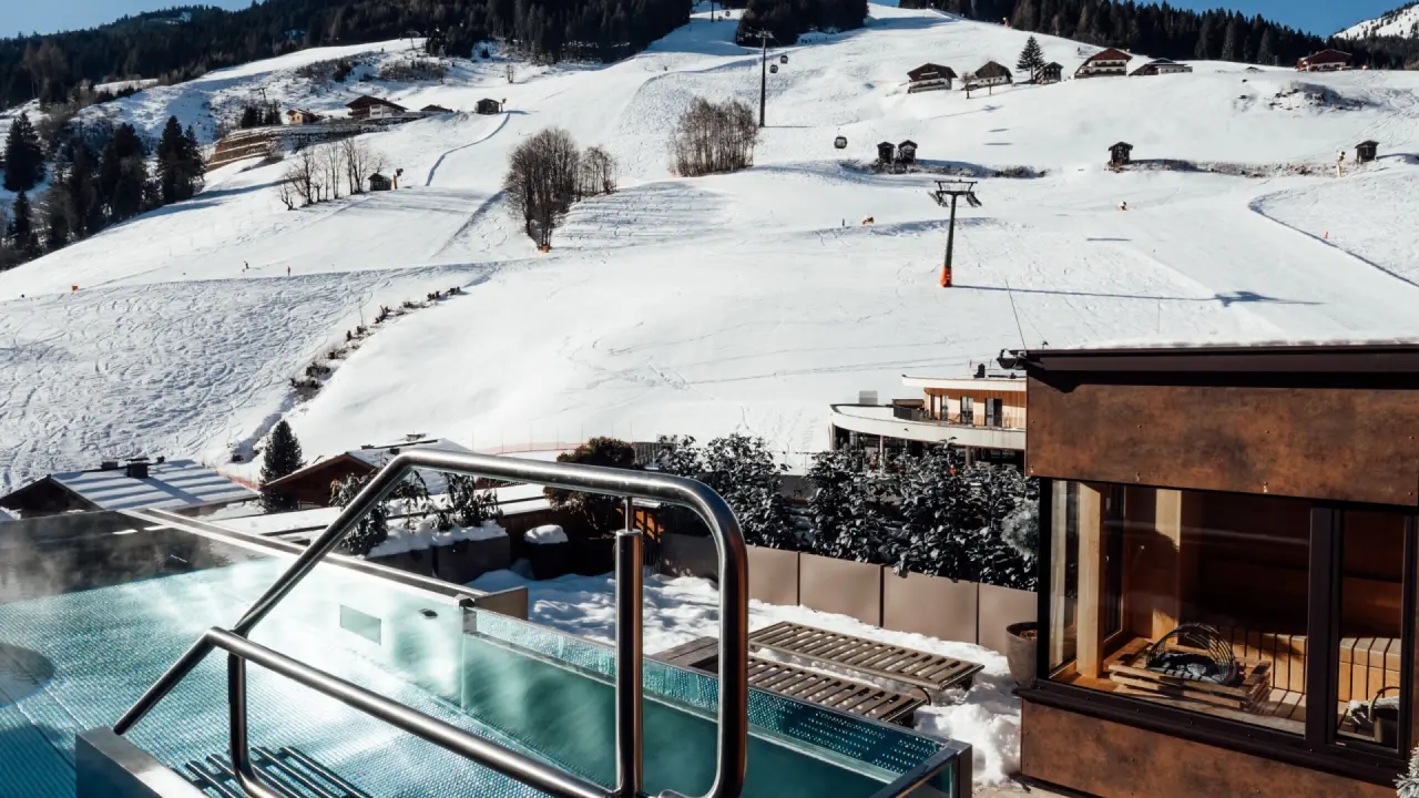 Beheizter Aussenpool und Sauna mit Blick auf die verschneiten Skipisten im Hotel Nesslerhof.