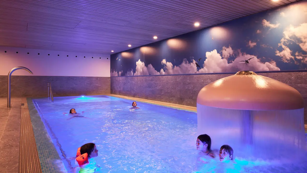 Beleuchteter Innenpool mit Wasserfall und Wolken-Wandmalerei im Hotel die Wälderin****s, ideal für Familien.