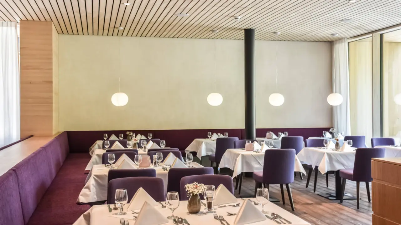 Modern eingerichteter Restaurantbereich im Hotel die Wälderin****s mit lila Stühlen und Holzakzenten.