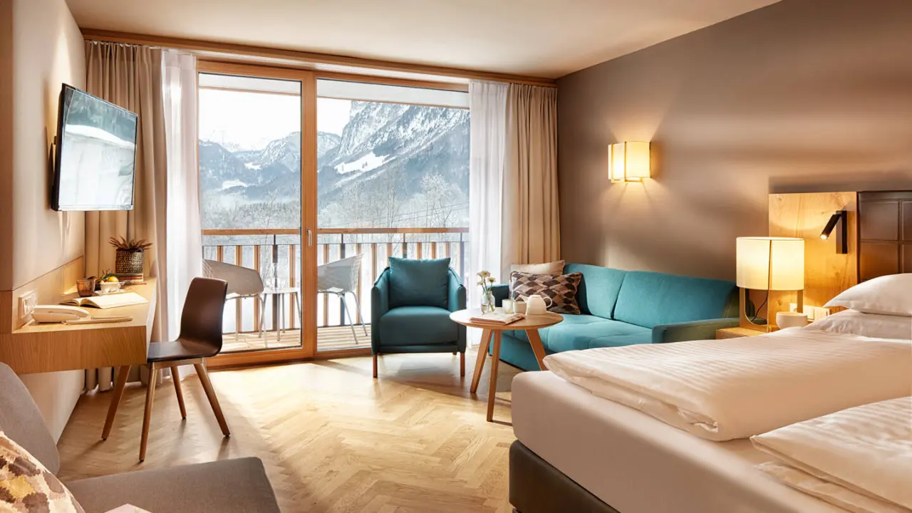 Komfortables Hotelzimmer im Hotel die Wälderin****s mit Balkon und malerischem Blick auf die verschneiten Berge.