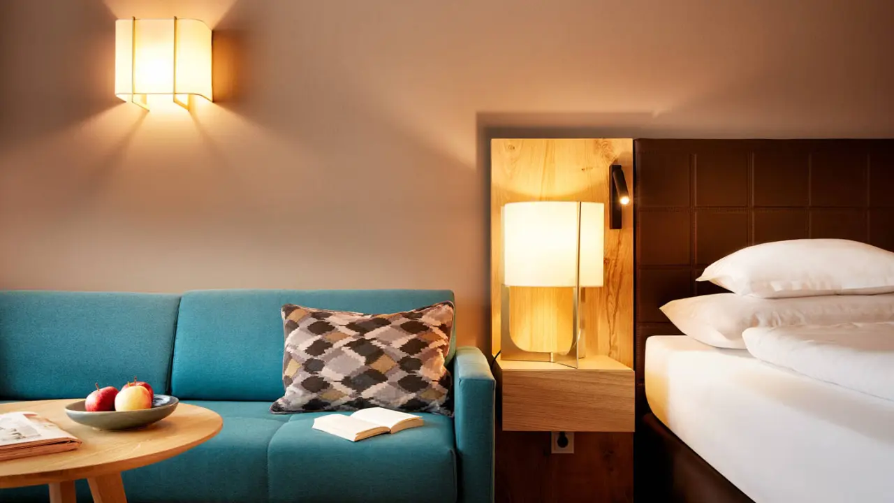 Gemütliches Hotelzimmer im Hotel die Wälderin****s mit Sofa, Leselampe und komfortablem Bett für entspannte Nächte.