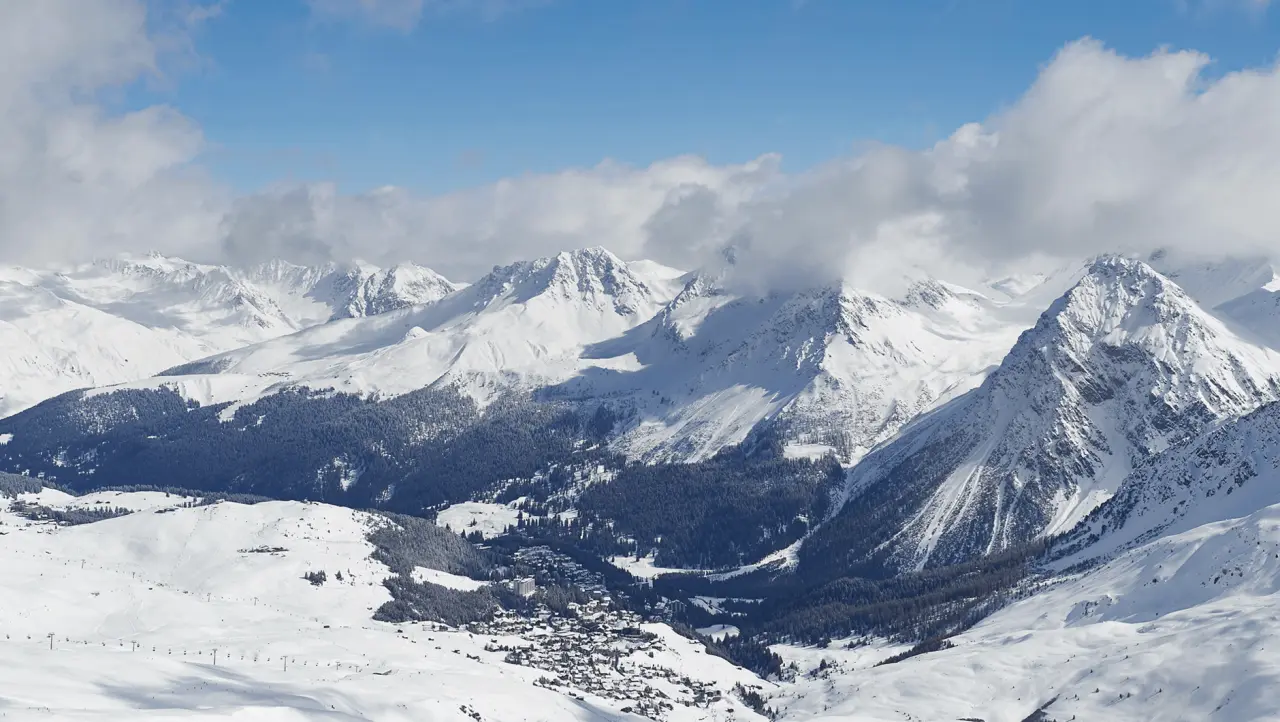 Panoramablick auf die verschneite Berglandschaft und das Dorf Arosa mit dem BelArosa Hotel im Winter.
