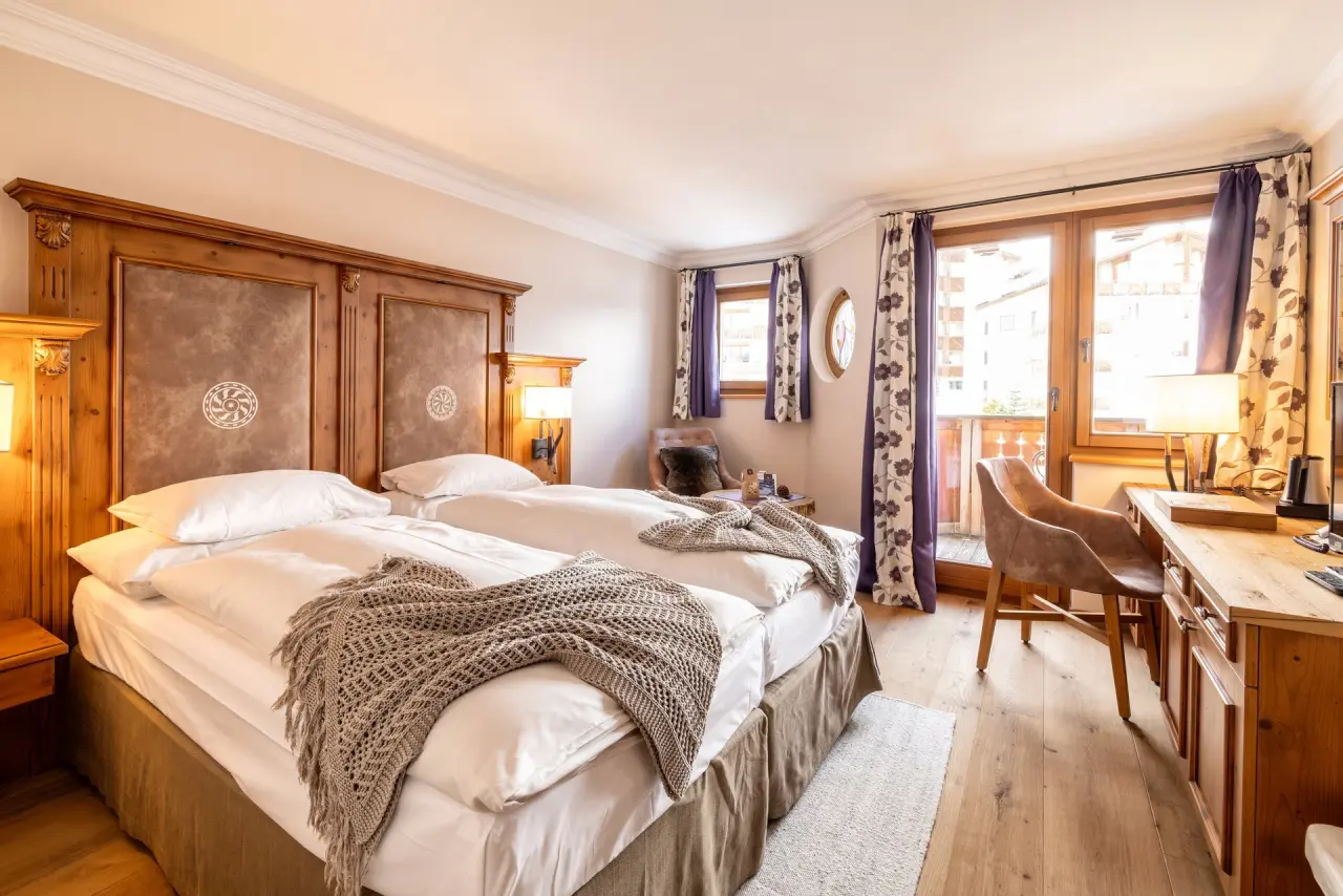 Gemütliches Doppelzimmer im BelArosa Hotel mit Holzelementen, bequemen Betten, Schreibtisch und Zugang zum Balkon.