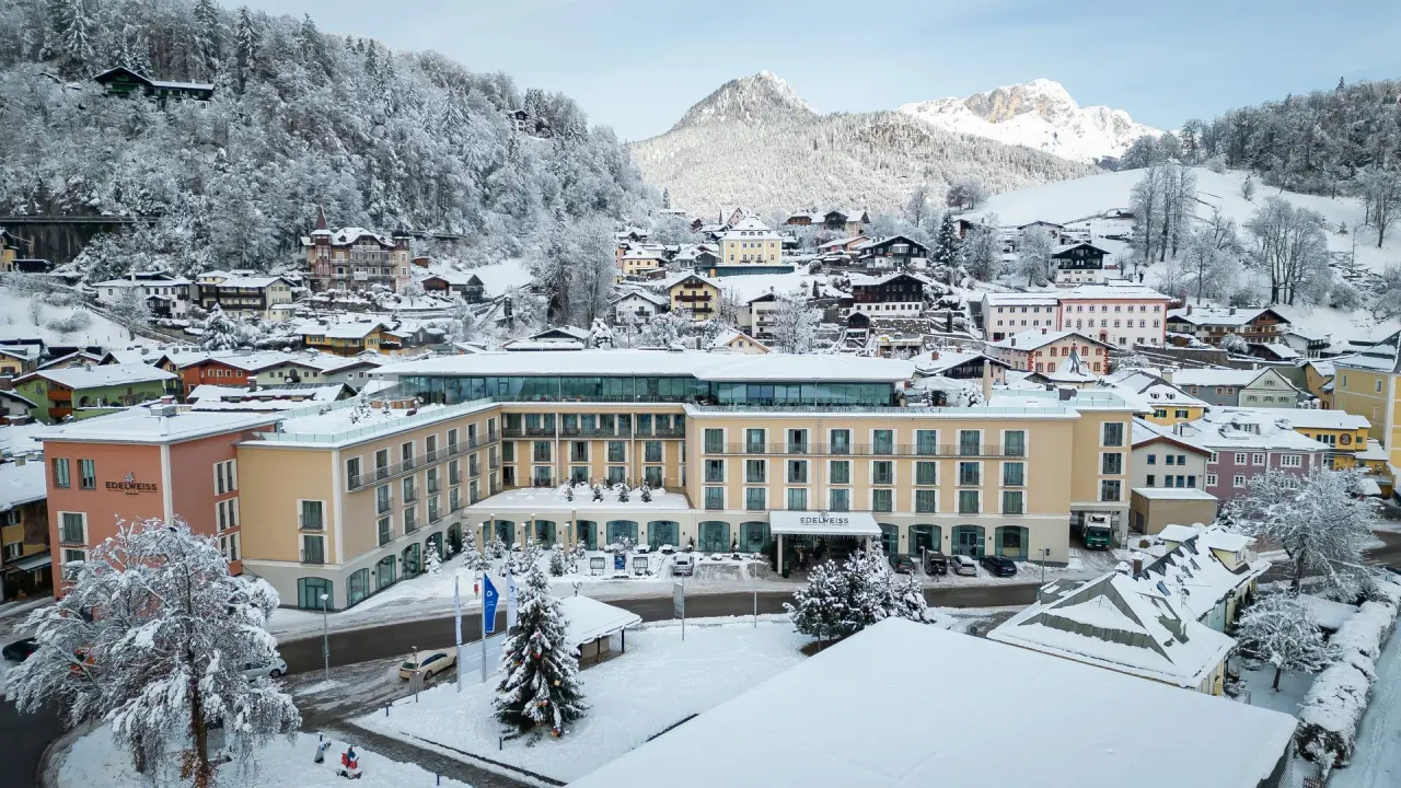 Winterliche Aussenansicht des Hotel EDELWEISS Berchtesgaden mit verschneiter Berglandschaft und Dorf.