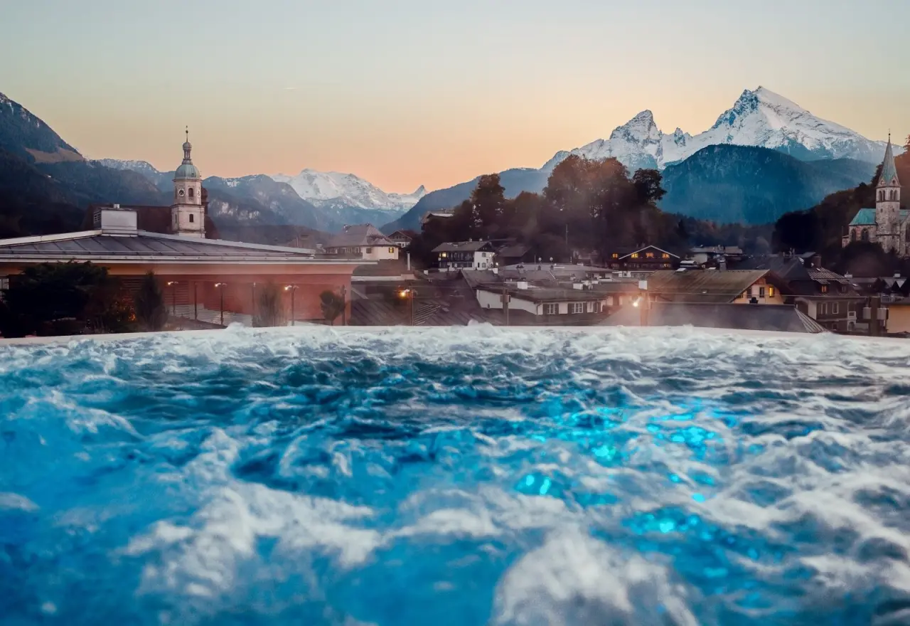 Beheizter Outdoor-Pool mit Berchtesgadener Alpenpanorama bei Sonnenuntergang im Hotel EDELWEISS Berchtesgaden.