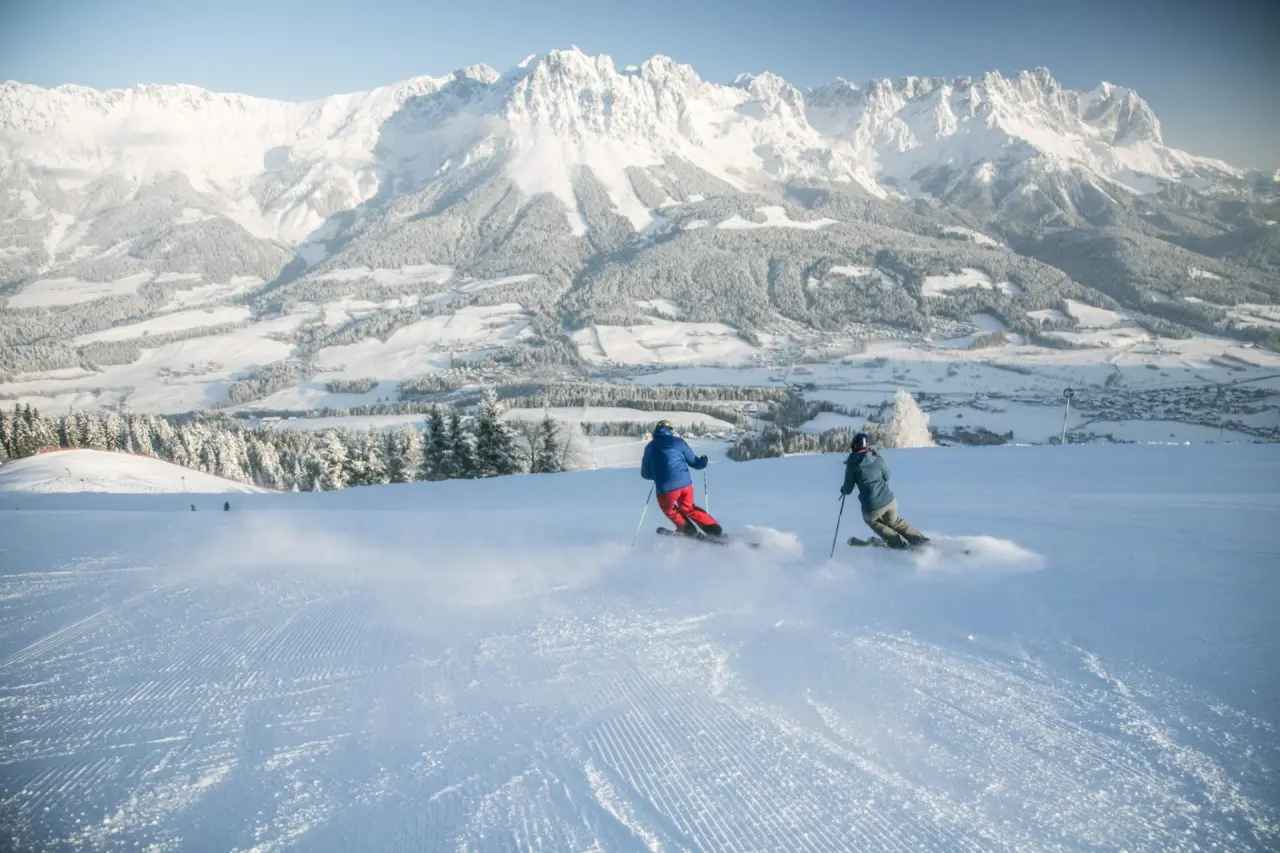 Skifahrer auf einer frisch präparierten Piste mit Panoramablick auf die verschneiten Alpen im Hotel Hochfilzer.