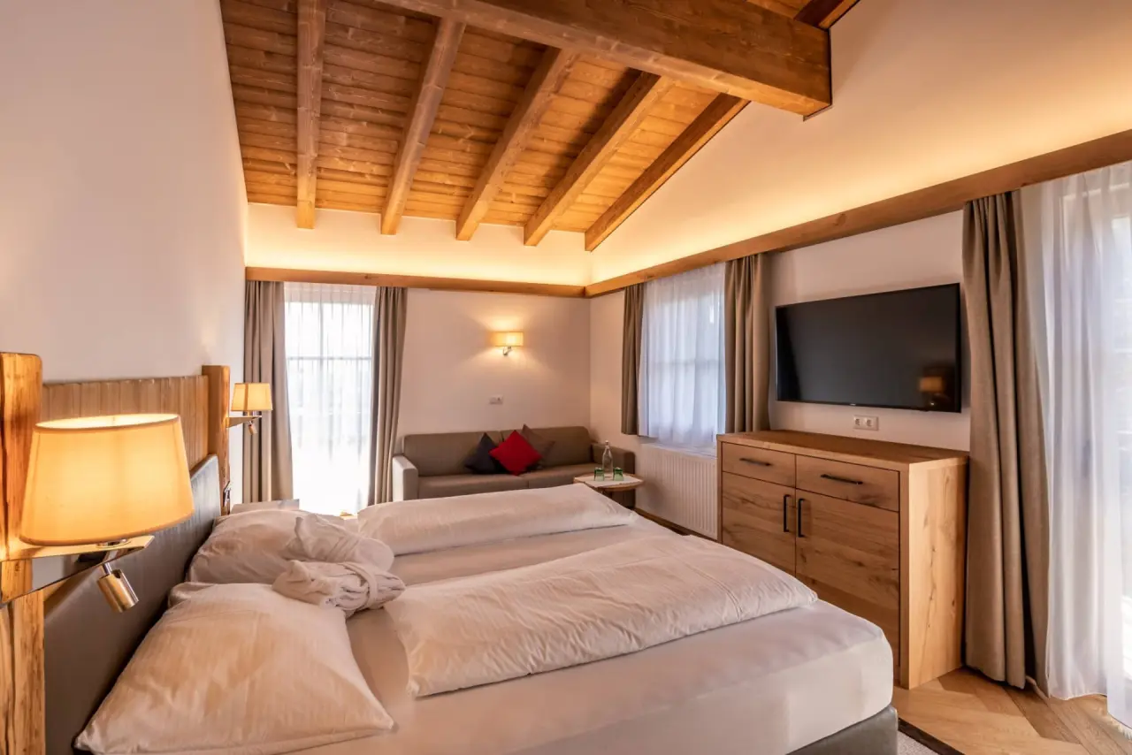 Gemütliches Doppelzimmer mit Holzbalkendecke, Sofa und TV im Hotel Hochfilzer.