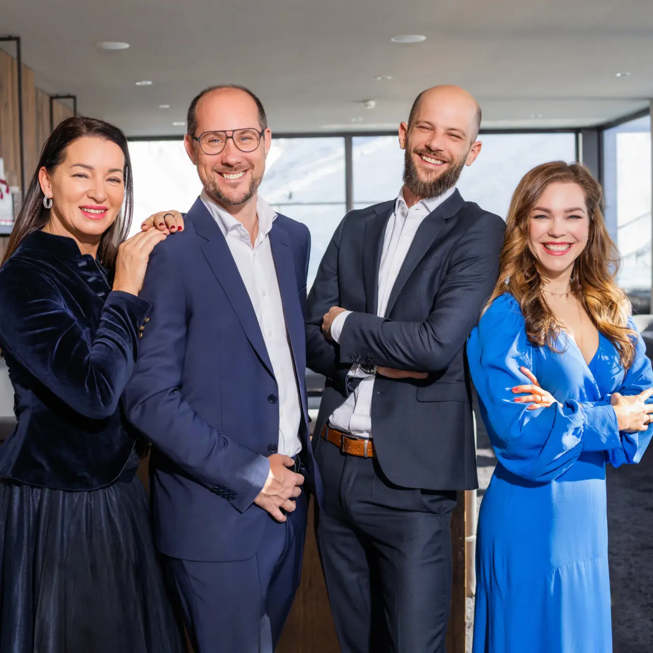 Das freundliche Team des Hotel Mooshaus lächelt vor der Kulisse der verschneiten Berge.