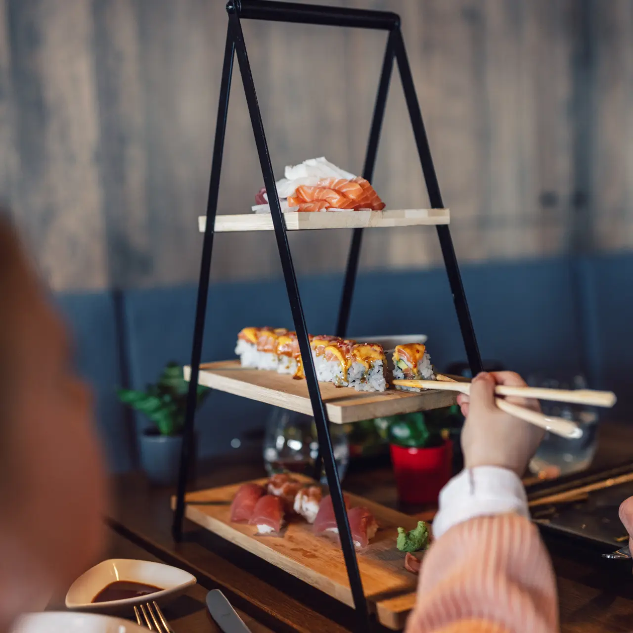 Frisch zubereitetes Sushi auf einer Etagere im stilvollen Restaurant des Hotel Mooshaus, mit Essstäbchen serviert.