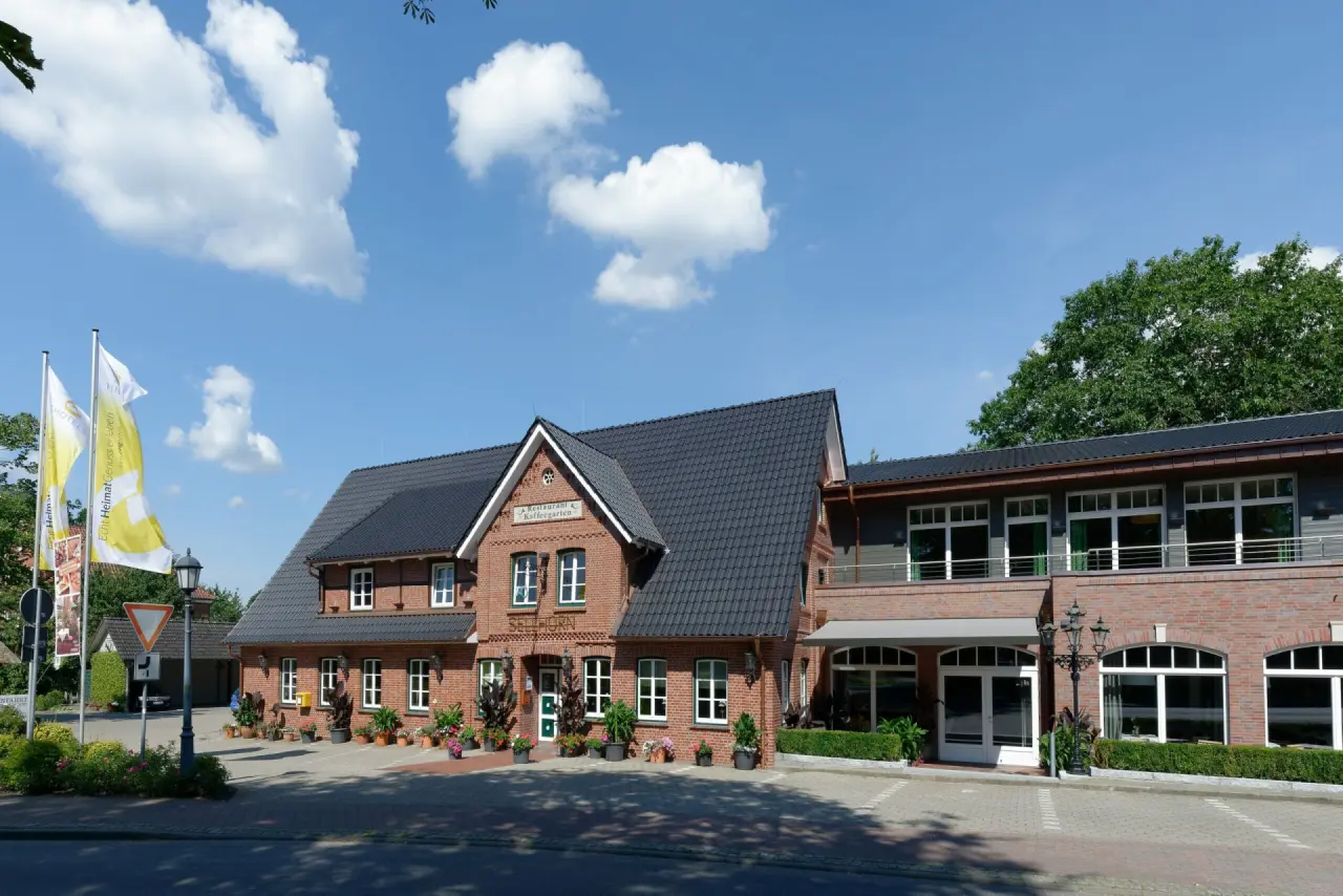 Aussenansicht des Ringhotel Sellhorn: traditionelle Backsteinfassade, dunkles Dach und blauer Himmel mit Wolken.