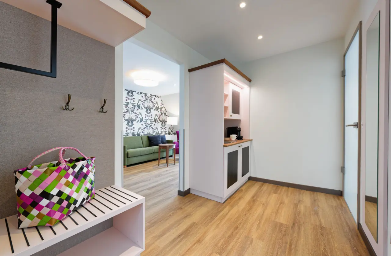 Eingangsbereich einer modernen Suite im Ringhotel Sellhorn mit Garderobe, Kaffeestation und Blick ins Wohnzimmer.