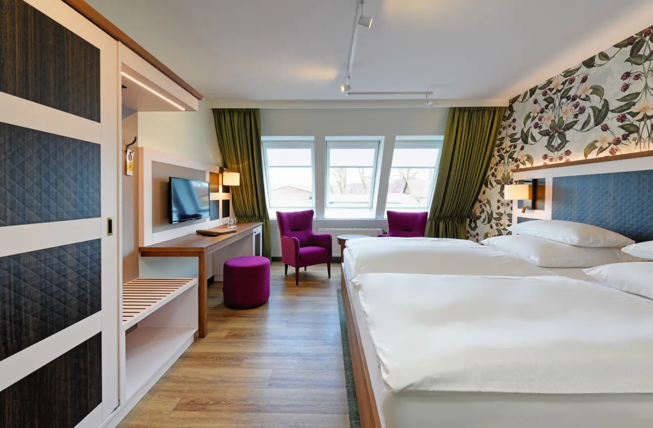 Komfortables Doppelzimmer im Ringhotel Sellhorn mit floraler Tapete, gemütlichen Sesseln und Schreibtisch.
