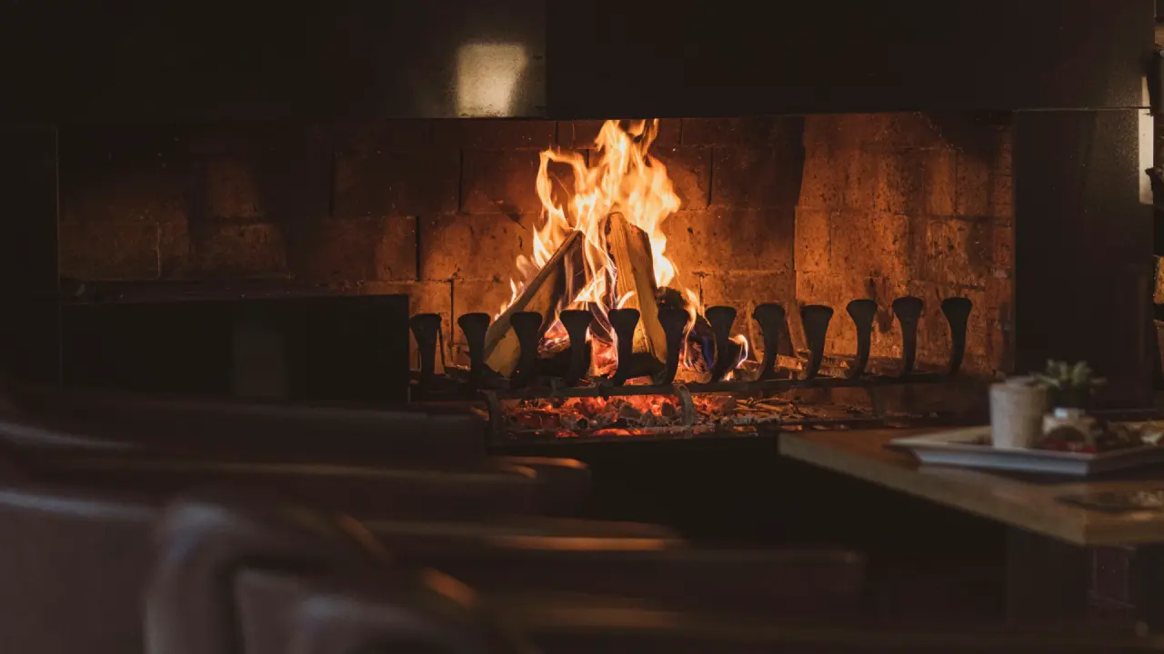 Gemütlicher Kamin mit knisterndem Feuer im Loungebereich des Hotel Zur Heidschnucke.