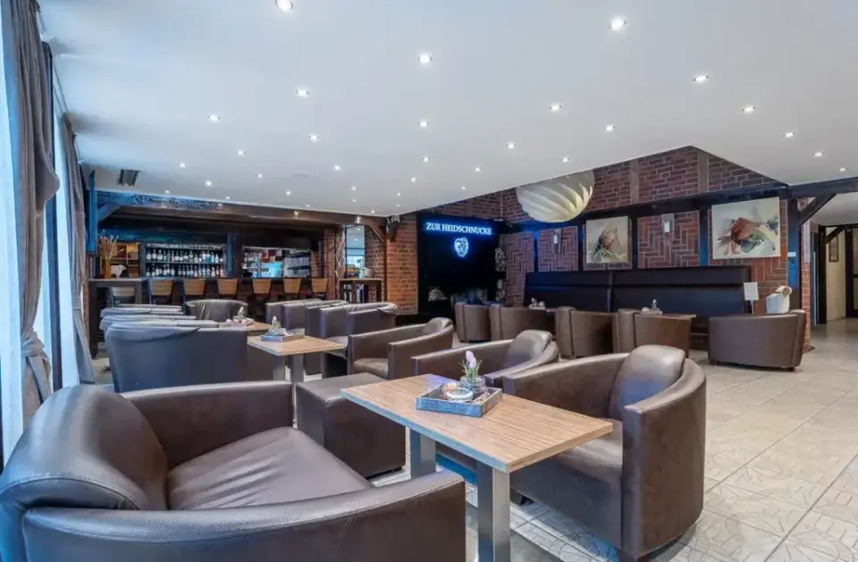 Gemütliche Hotelbar und Lounge mit Ledersesseln und Backsteinwand im Hotel Zur Heidschnucke.