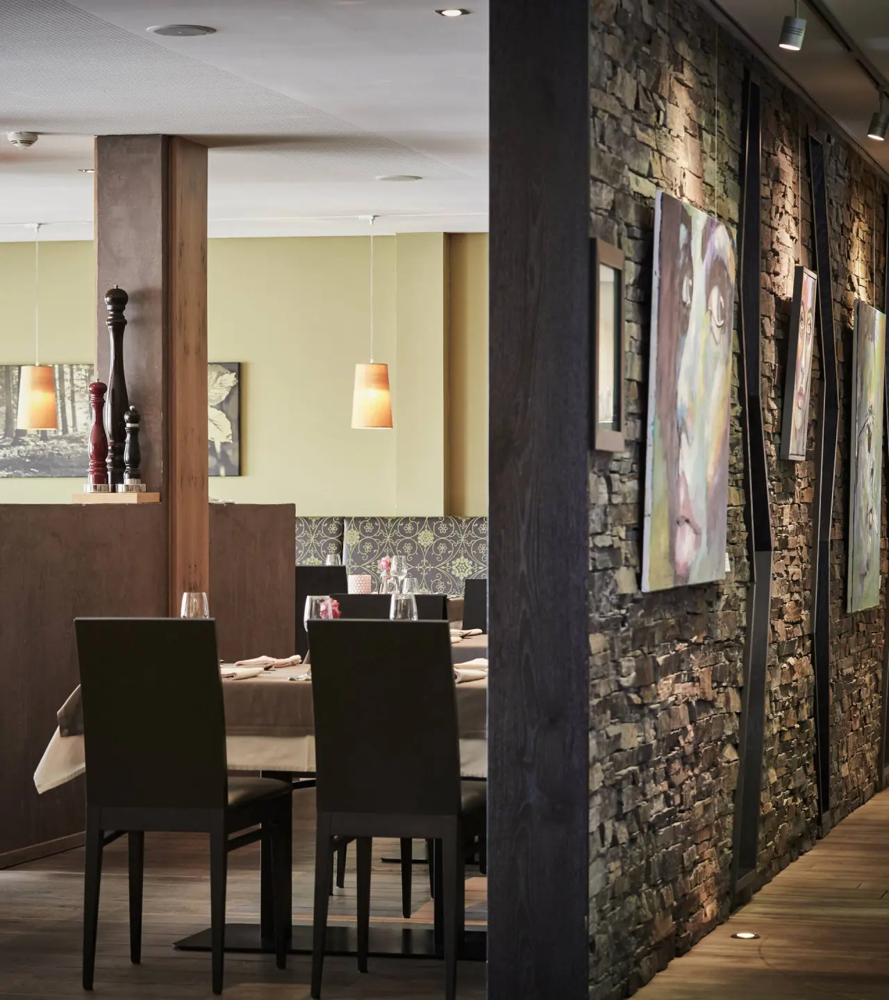 Stilvolles Restaurant im DAS KRONTHALER****S mit moderner Steinwand, Kunst und elegant gedeckten Tischen.