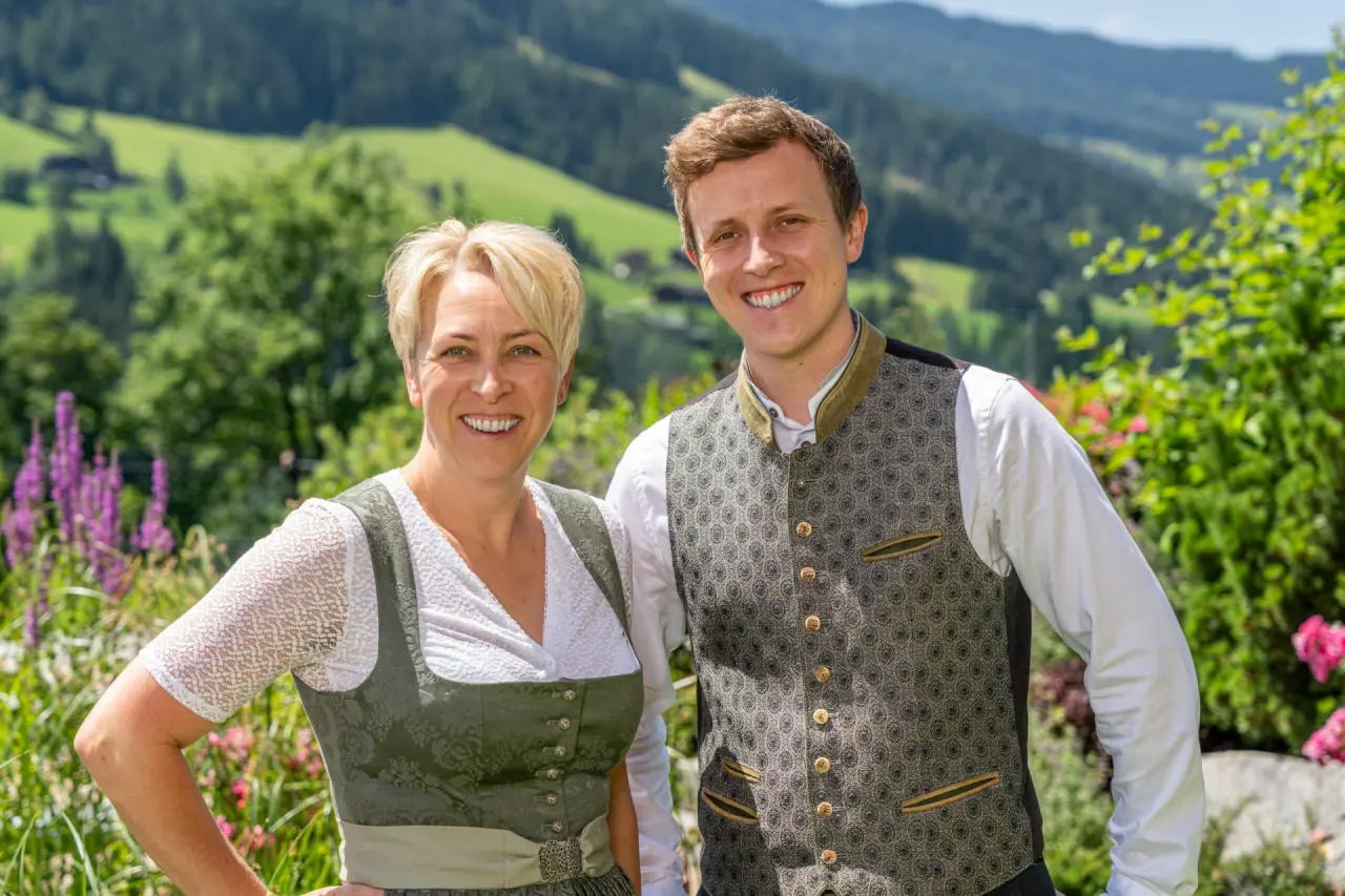 Die freundlichen Gastgeber des Alpbacherhof****s Mountain & Spa Resort in Tracht vor der malerischen Berglandschaft.