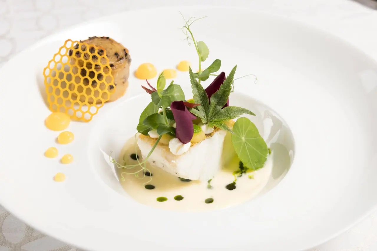 Exquisit angerichteter Fischgang mit feiner Sauce und Kräutern im Restaurant des Alpbacherhof****s Mountain & Spa Resort.