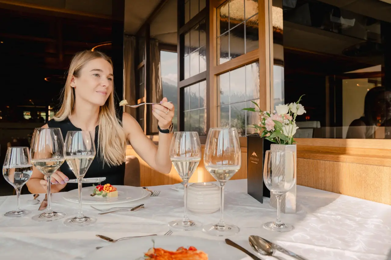 Gast genießt ein elegantes Abendessen im Restaurant des Alpbacherhof****s Mountain & Spa Resort mit Bergblick.