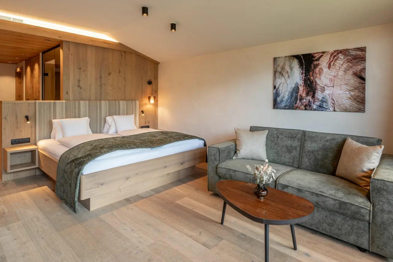Modernes Doppelzimmer mit Holzelementen und gemütlicher Sitzecke im Alpbacherhof****s - Mountain & Spa Resort.