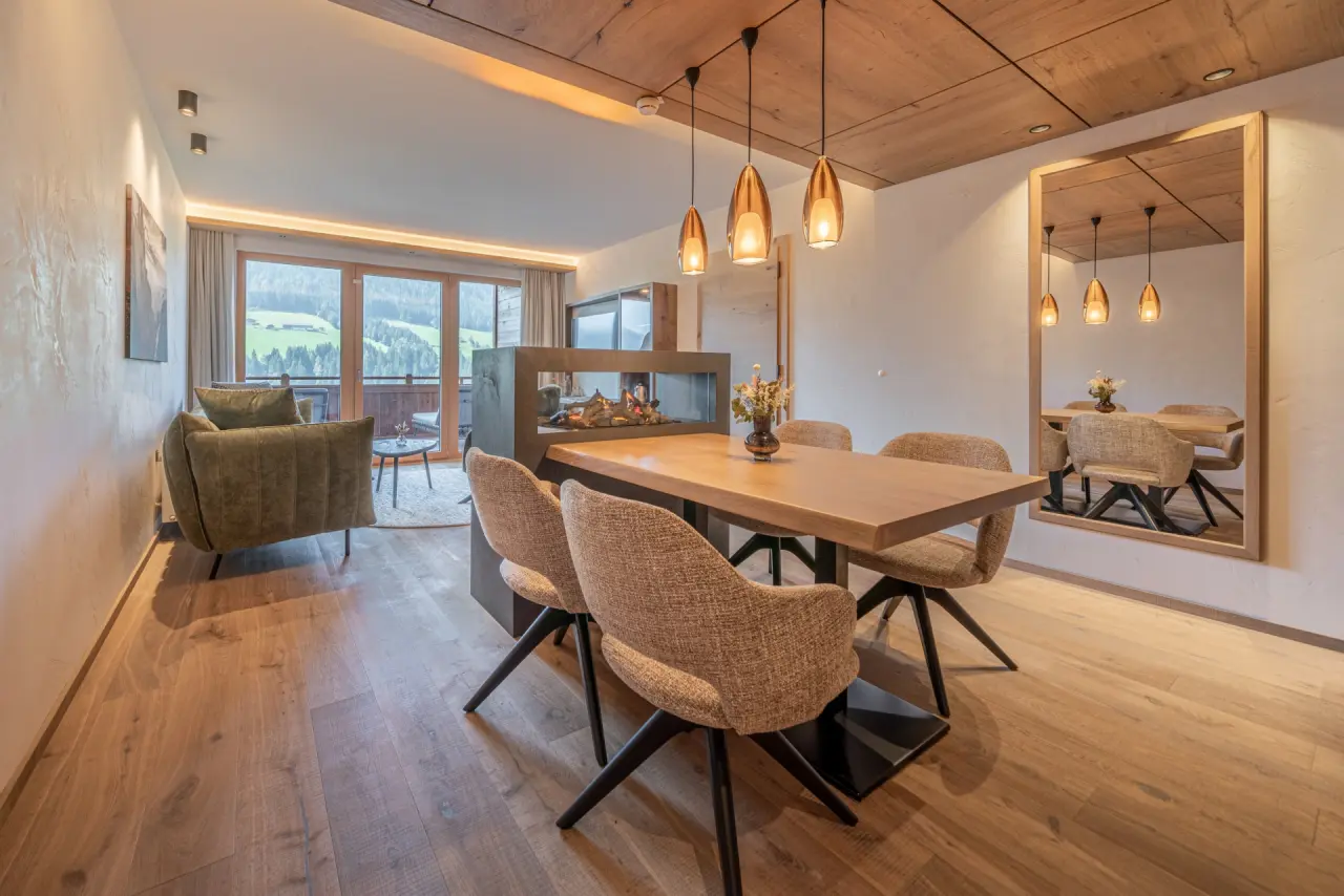 Geräumige Suite im Alpbacherhof****s mit Essbereich, Kamin, Wohnzimmer und Bergblick. Modernes Design und Holzelemente.