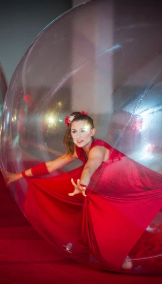 Künstlerin in rotem Kleid in einer Kugel bei einer Veranstaltung im Klosterhof - Alpine Hideaway & Spa.