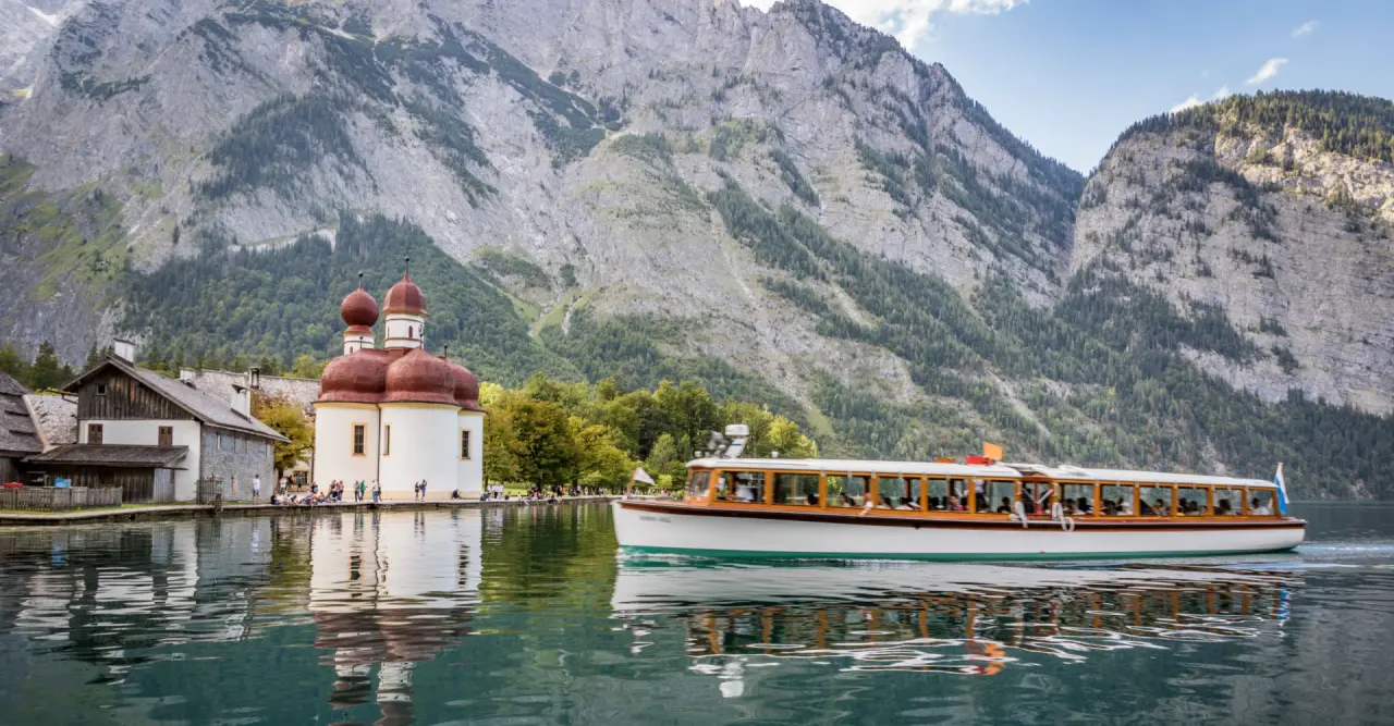 Panoramablick auf St. Bartholomä am Königssee mit Boot und Alpenkulisse, nahe dem Klosterhof - Alpine Hideaway & Spa.