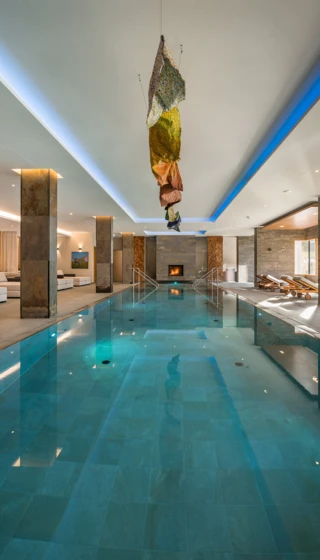 Grosszügiger Innenpool mit Kamin und Lounge-Bereich im Klosterhof - Alpine Hideaway & Spa.