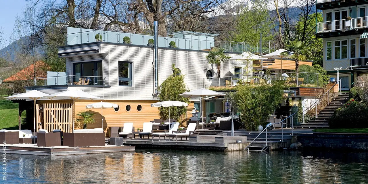 Moderne Architektur von KOLLERs Hotel direkt am See mit Holzstegen, Liegen und Lounge-Bereichen im Sonnenlicht.