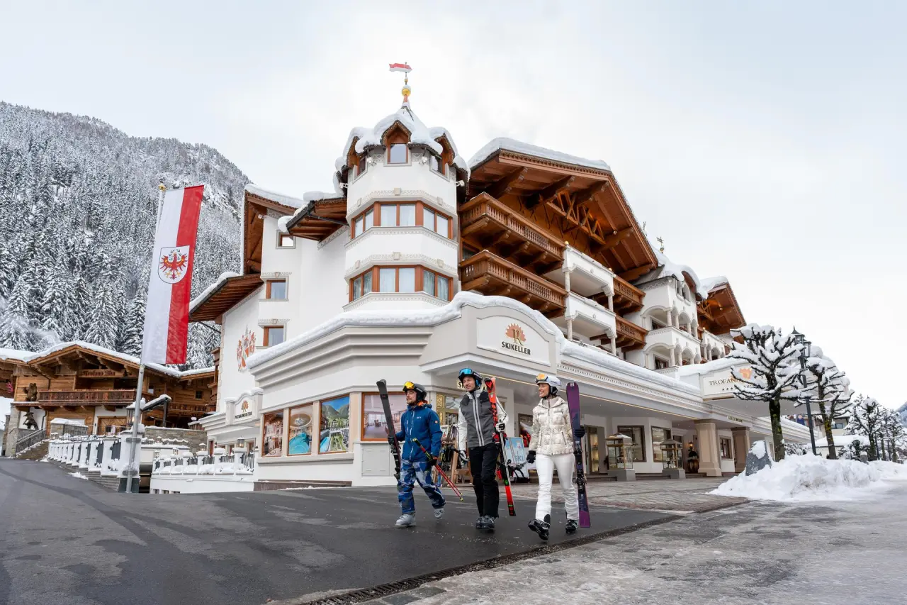 Luxuriöses Hotel Trofana Royal in Ischgl im Winter mit Skifahrern und verschneiter Berglandschaft.
