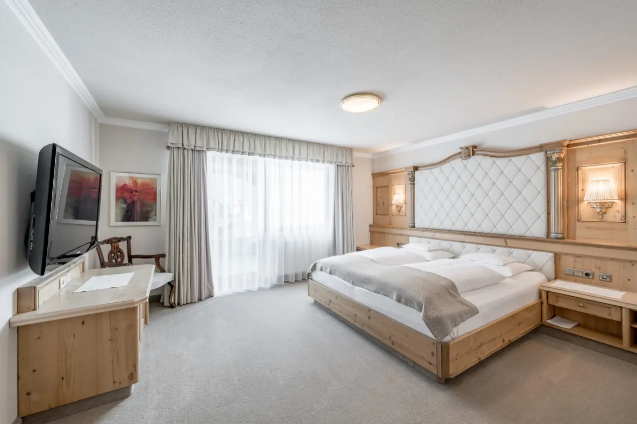 Gemütliches Doppelzimmer im alpinen Stil mit Holzelementen und bequemen Betten im Hotel Trofana Royal.