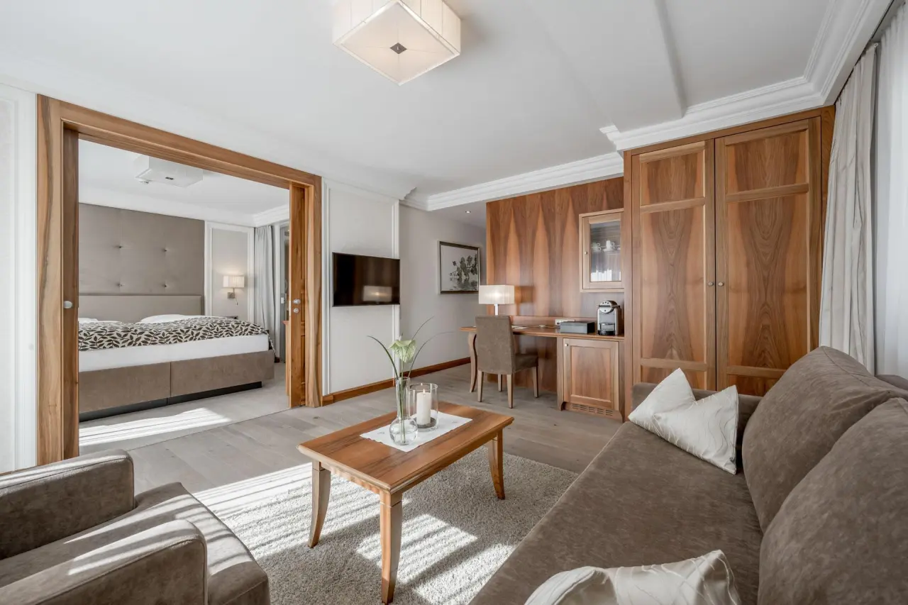 Elegante Suite im Hotel Trofana Royal mit separatem Schlaf- und Wohnbereich, hochwertigen Holzmöbeln und viel Tageslicht.