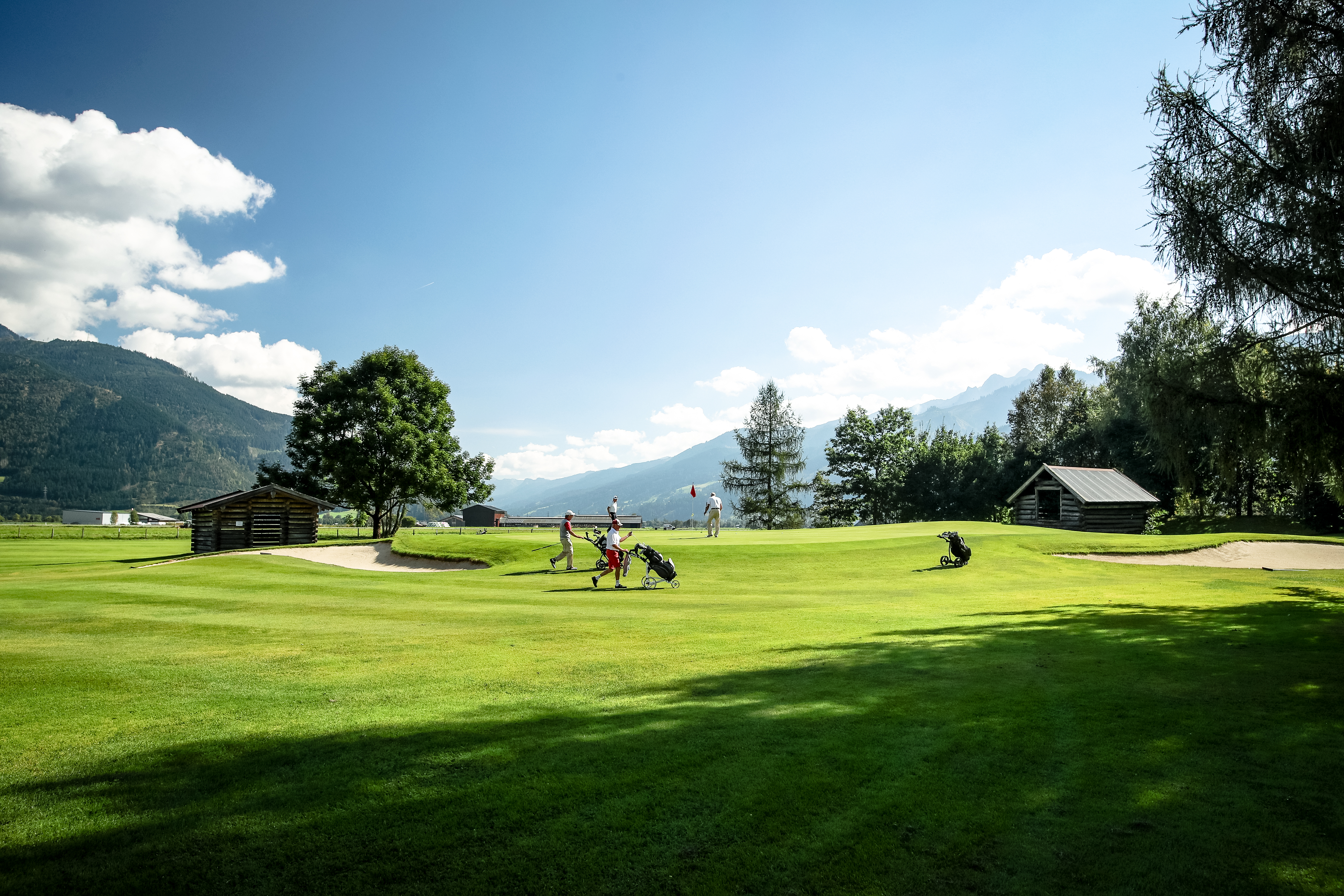 Das Alpenhaus Kaprun in Kaprun – Golfplatz mit Bergpanorama und Bäumen | Wellnesshotel Pinzgau