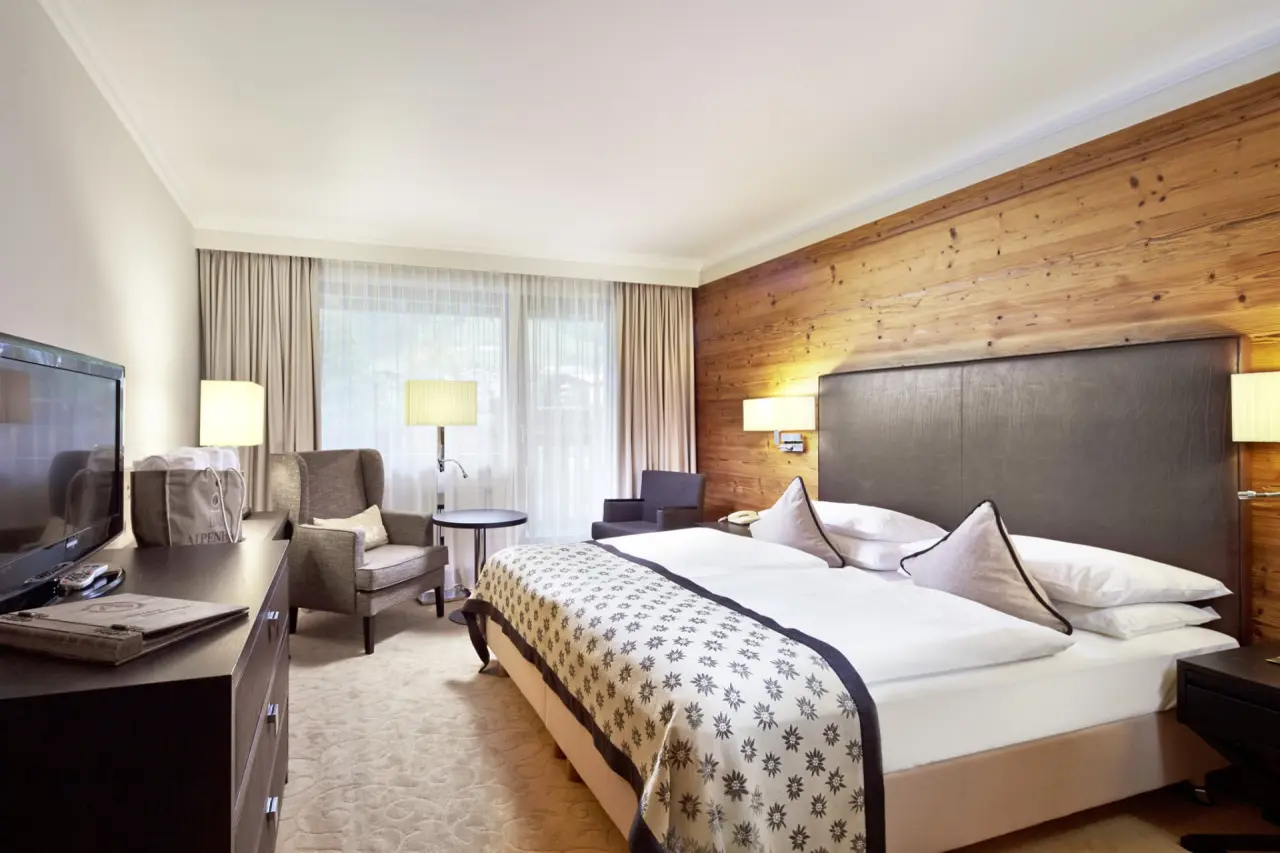 Gemütliches Doppelzimmer mit Holzwand und Sitzbereich im Das Alpenhaus Kaprun.