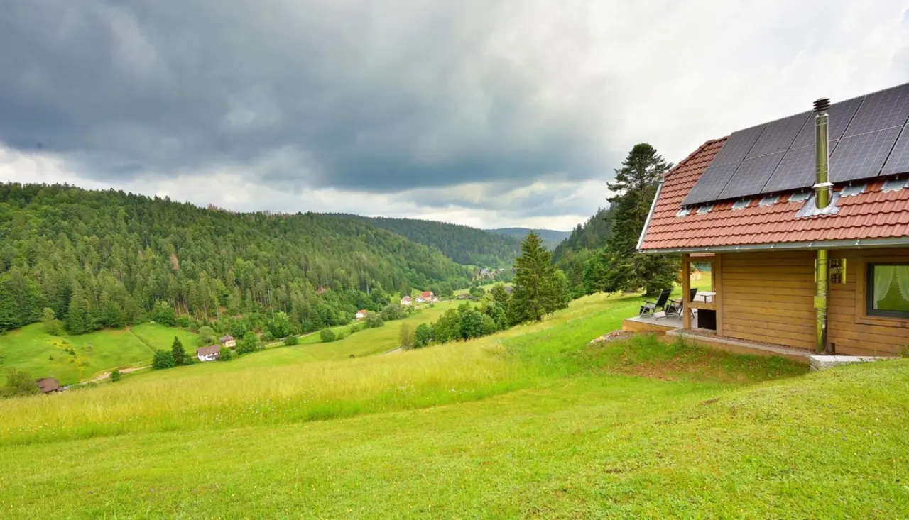 Holzhaus mit Solaranlage und Terrasse vor bewaldetem Tal im Schwarzwald, Hotel Rößle.