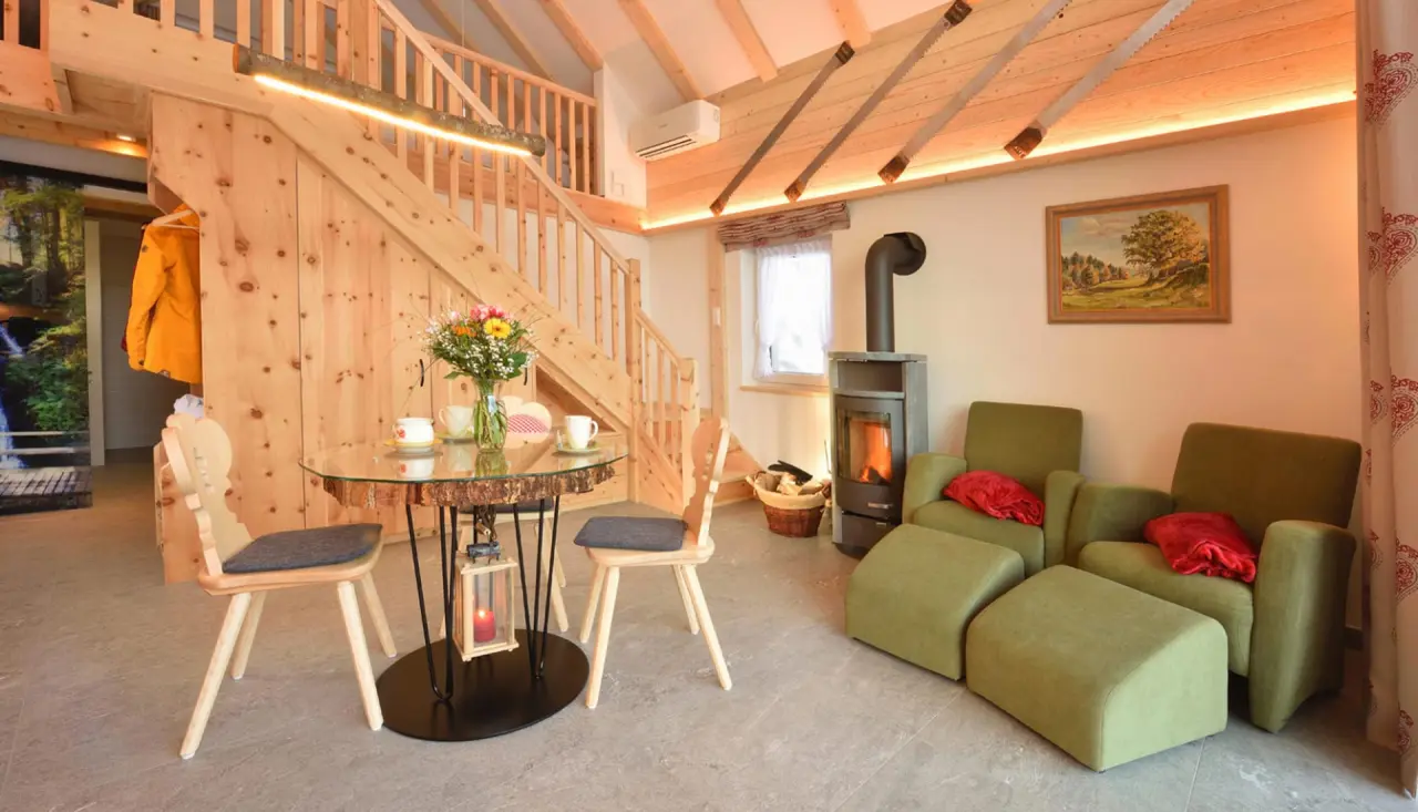 Gemütliche Suite im Hotel Rößle mit Kamin, Esstisch und rustikaler Holzarchitektur für entspannte Wellness-Aufenthalte.