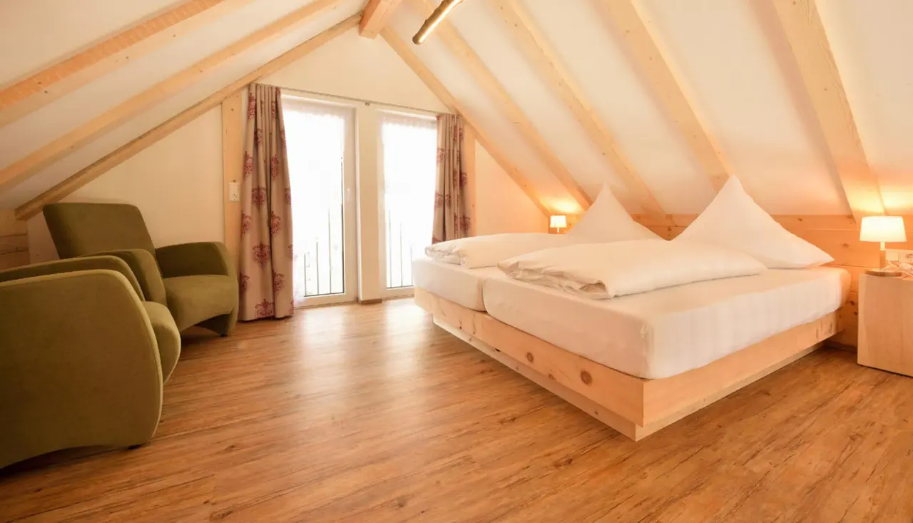 Gemütliches Hotelzimmer im Dachgeschoss des Hotel Rößle mit Holzbalken, Doppelbett und bequemen Sesseln.