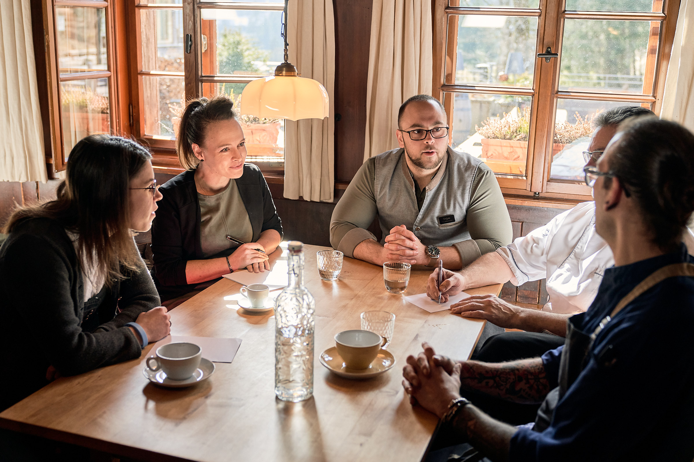 Hotel Die Halde in Oberried-Hofsgrund – Gruppe von Personen bei einem Gespräch am Tisch | Wellnesshotel Schwarzwald