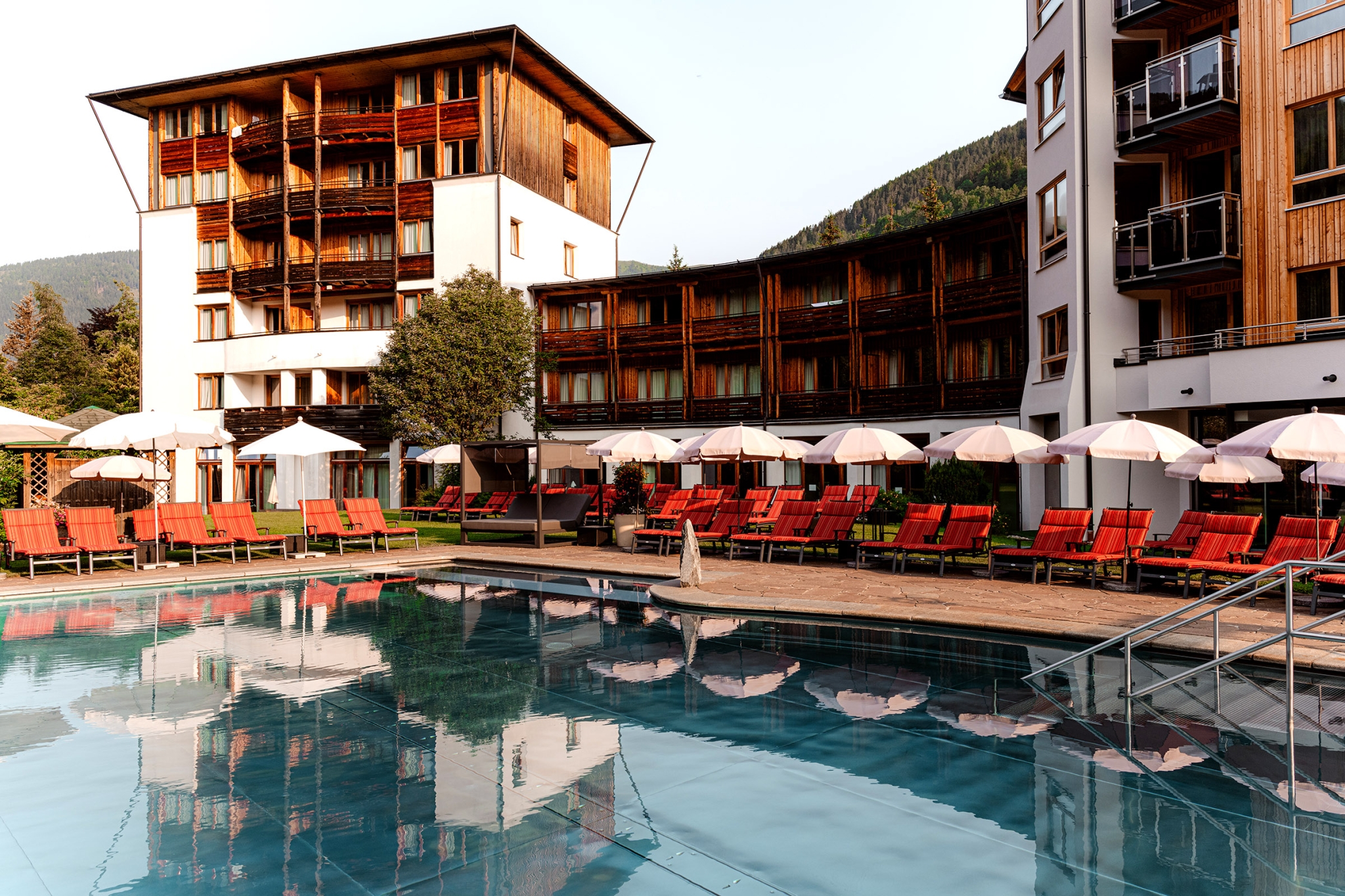Hotel DIE POST in Bad Kleinkirchheim – Außenpool mit Liegen und Hotelgebäude | Wellnesshotel Kärnten