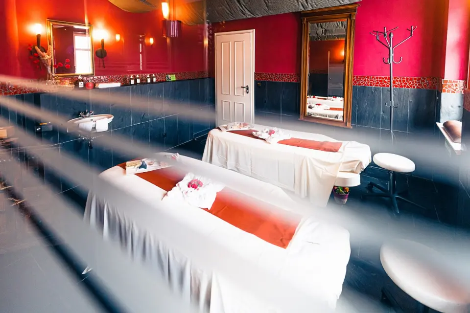 Behandlungsraum für Paarmassagen mit roten Wänden und zwei Massageliegen im Spa des Hotel BEI SCHUMANN.