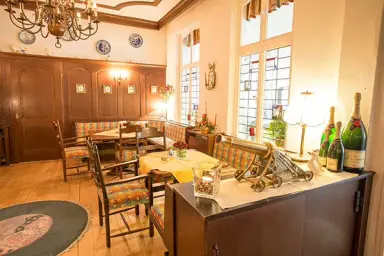 Traditioneller Restaurantbereich im Nordseehotel Freese mit Holztäfelung, gemütlichen Sitzecken und Buntglasfenstern.
