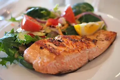 Gegrillter Lachs mit frischem Salat und Zitrone, serviert im Restaurant des Nordseehotel Freese.