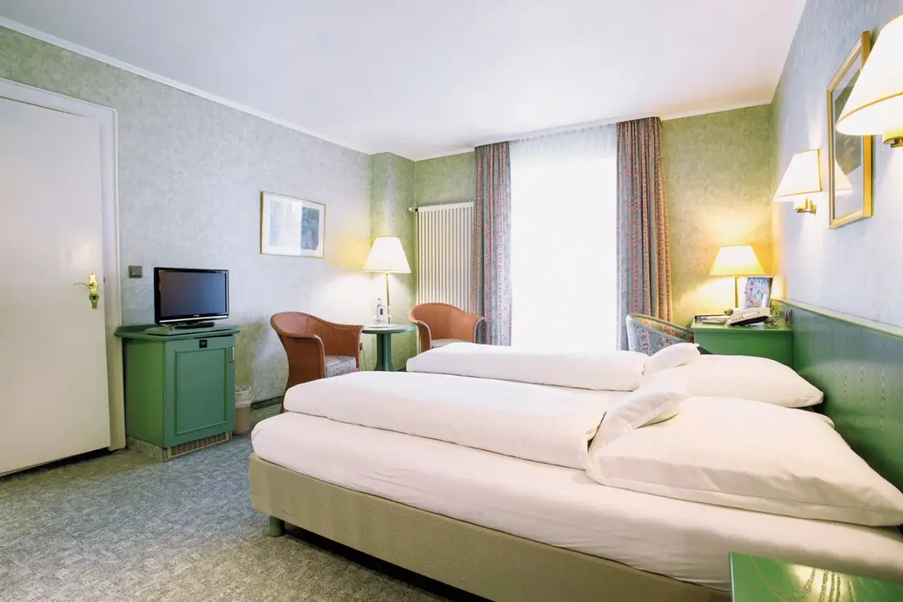 Gemütliches Doppelzimmer im Nordseehotel Freese mit zwei Einzelbetten, TV und Sitzgelegenheit.
