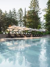 Einladender Aussenpool mit Liegestühlen und Sonnenschirmen umgeben von Bäumen im Steigenberger Sonnenhof.